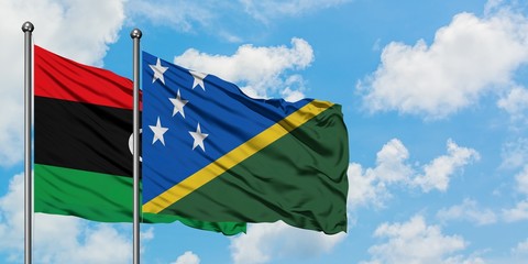 Libya and Solomon Islands flag waving in the wind against white cloudy blue sky together. Diplomacy concept, international relations.