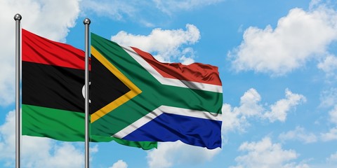 Libya and South Africa flag waving in the wind against white cloudy blue sky together. Diplomacy concept, international relations.