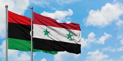 Libya and Syria flag waving in the wind against white cloudy blue sky together. Diplomacy concept, international relations.