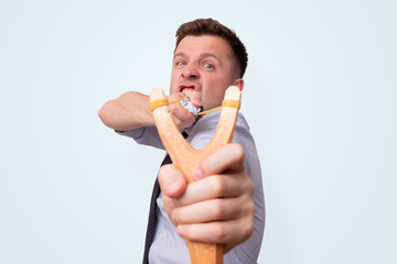 Young caucasian office manager with a slingshot pointing on you.