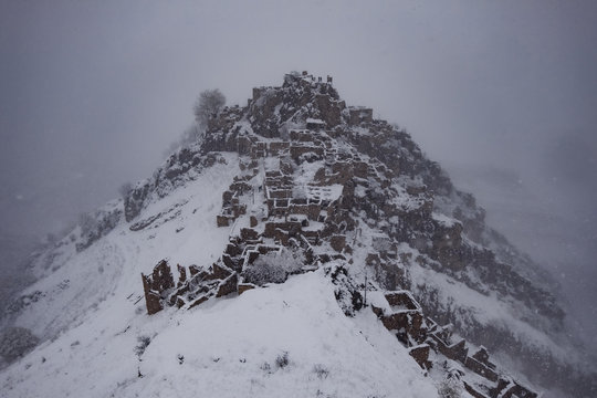 Aerial view of abandoned city Gamsutl in foggy snowy winter Caucasus mountains, Dagestan, Russia
