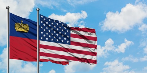 Liechtenstein and United States flag waving in the wind against white cloudy blue sky together. Diplomacy concept, international relations.