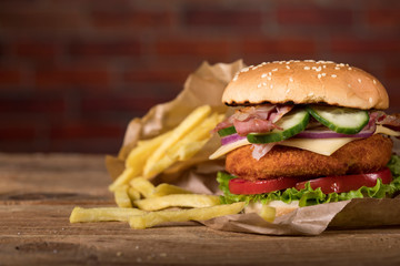 Fresh burger on wooden table and brick wall background