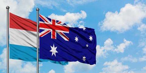 Luxembourg and Australia flag waving in the wind against white cloudy blue sky together. Diplomacy concept, international relations.