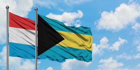 Luxembourg and Bahamas flag waving in the wind against white cloudy blue sky together. Diplomacy concept, international relations.
