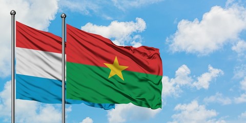 Luxembourg and Burkina Faso flag waving in the wind against white cloudy blue sky together. Diplomacy concept, international relations.