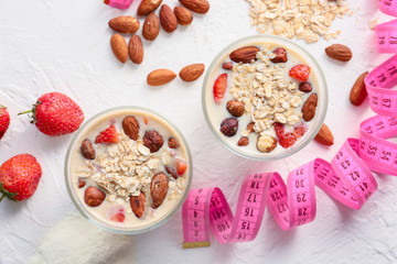 Glasses of protein shake with measuring tape on white background