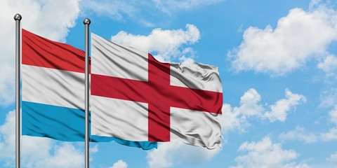 Luxembourg and England flag waving in the wind against white cloudy blue sky together. Diplomacy concept, international relations.