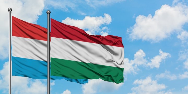 Luxembourg and Hungary flag waving in the wind against white cloudy blue sky together. Diplomacy concept, international relations.