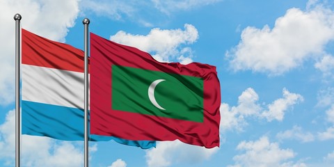 Luxembourg and Maldives flag waving in the wind against white cloudy blue sky together. Diplomacy concept, international relations.