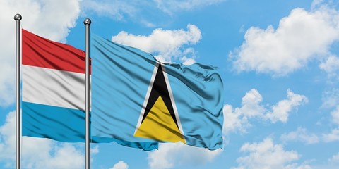 Luxembourg and Saint Lucia flag waving in the wind against white cloudy blue sky together. Diplomacy concept, international relations.