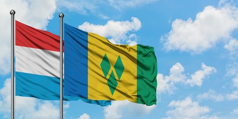 Luxembourg and Saint Vincent And The Grenadines flag waving in the wind against white cloudy blue sky together. Diplomacy concept, international relations.