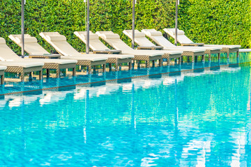 Umbrella and chair sofa around outdoor swimming pool in hotel resort for holiday vacation
