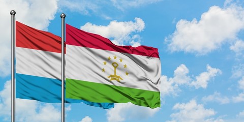 Luxembourg and Tajikistan flag waving in the wind against white cloudy blue sky together. Diplomacy concept, international relations.