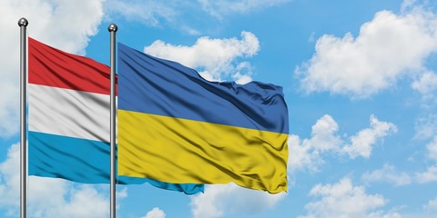 Luxembourg and Ukraine flag waving in the wind against white cloudy blue sky together. Diplomacy concept, international relations.