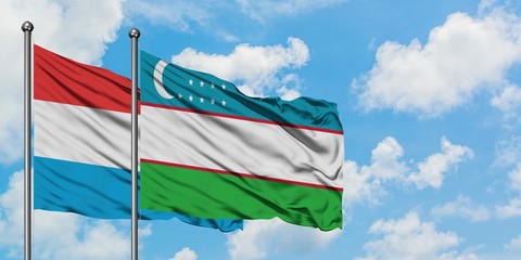 Luxembourg and Uzbekistan flag waving in the wind against white cloudy blue sky together. Diplomacy concept, international relations.