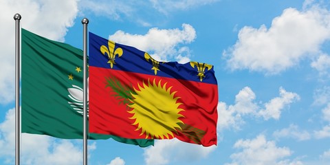 Macao and Guadeloupe flag waving in the wind against white cloudy blue sky together. Diplomacy concept, international relations.