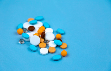 Multi-colored pills on a blue background close-up, with copy space for text