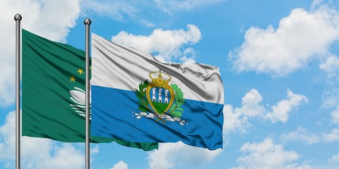 Macao and San Marino flag waving in the wind against white cloudy blue sky together. Diplomacy...