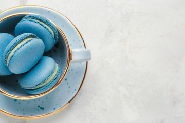 Cup with tasty macarons on white background