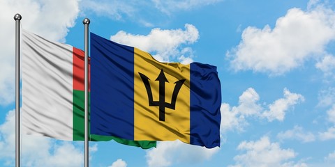 Madagascar and Barbados flag waving in the wind against white cloudy blue sky together. Diplomacy concept, international relations.