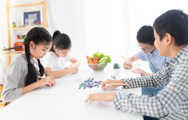 asian children training to drawing and paint image, they feeling happy and smile, they use pencil and crayon color in art training time