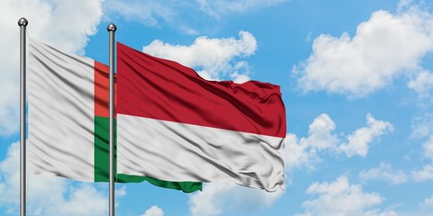 Madagascar and Monaco flag waving in the wind against white cloudy blue sky together. Diplomacy concept, international relations.