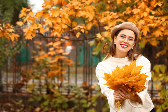 Stylish young woman with leaves in autumn park