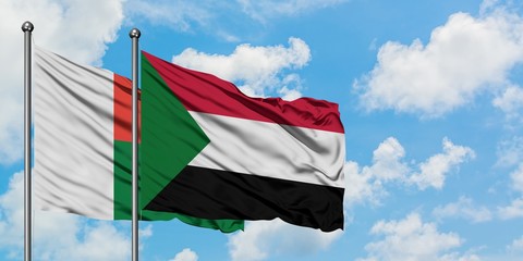 Madagascar and Sudan flag waving in the wind against white cloudy blue sky together. Diplomacy concept, international relations.