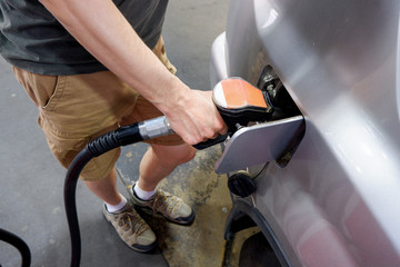 A man hand holding pump filling gasoline. Pumping petrol into the tank. A car refuel on gas station