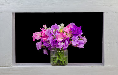 A bunch of sweet pea flowers framed black background