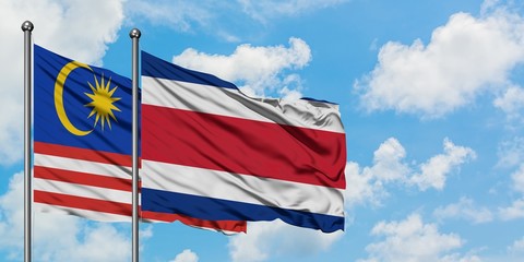 Malaysia and Costa Rica flag waving in the wind against white cloudy blue sky together. Diplomacy concept, international relations.
