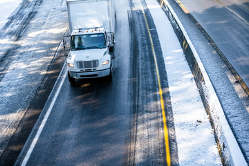 Medium Power rig semi Truck with roof spoiler running on the winter snowy road with divided lines
