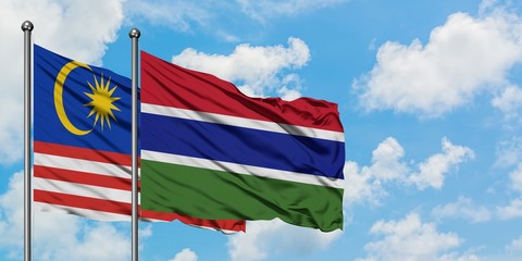 Malaysia and Gambia flag waving in the wind against white cloudy blue sky together. Diplomacy concept, international relations.