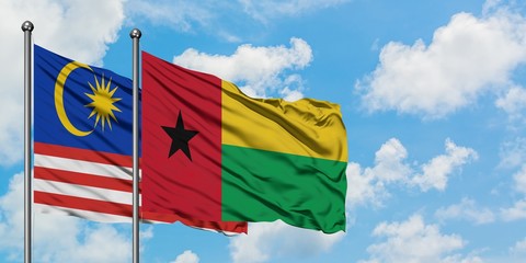 Malaysia and Guinea Bissau flag waving in the wind against white cloudy blue sky together. Diplomacy concept, international relations.