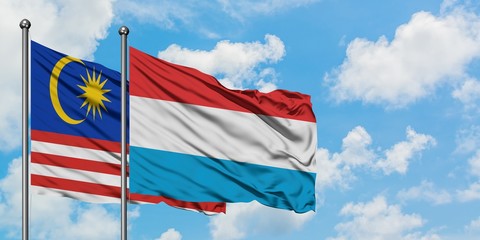 Malaysia and Luxembourg flag waving in the wind against white cloudy blue sky together. Diplomacy concept, international relations.