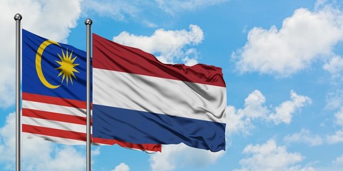 Malaysia and Netherlands flag waving in the wind against white cloudy blue sky together. Diplomacy concept, international relations.