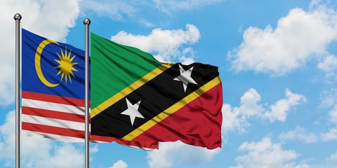 Malaysia and Saint Kitts And Nevis flag waving in the wind against white cloudy blue sky together. Diplomacy concept, international relations.