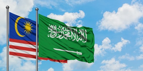 Malaysia and Saudi Arabia flag waving in the wind against white cloudy blue sky together. Diplomacy concept, international relations.