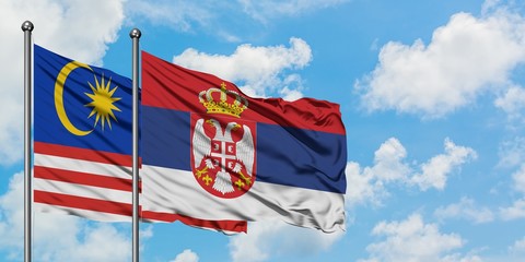 Malaysia and Serbia flag waving in the wind against white cloudy blue sky together. Diplomacy concept, international relations.