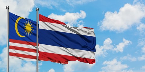 Malaysia and Thailand flag waving in the wind against white cloudy blue sky together. Diplomacy concept, international relations.