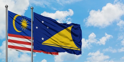 Malaysia and Tokelau flag waving in the wind against white cloudy blue sky together. Diplomacy concept, international relations.