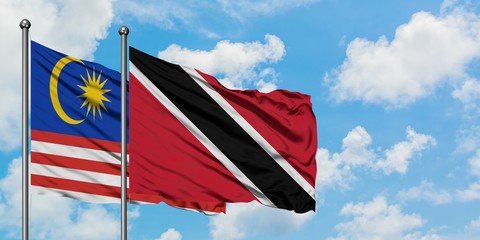Malaysia and Trinidad And Tobago flag waving in the wind against white cloudy blue sky together. Diplomacy concept, international relations.