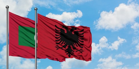 Maldives and Albania flag waving in the wind against white cloudy blue sky together. Diplomacy concept, international relations.