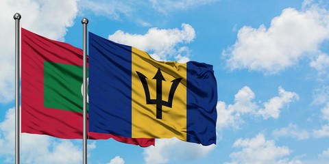 Maldives and Barbados flag waving in the wind against white cloudy blue sky together. Diplomacy concept, international relations.