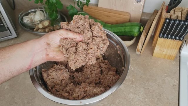 Home cooking - Taking and checking handful of previously cooked and seasoned ground beef making stuffing for croquet or wraps with meat filling.