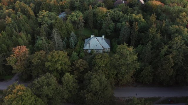 4K. Drone shot. Abandoned house in a dense forest at sunset day. Aerial view of a lonely house in the forest.