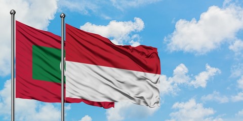 Maldives and Indonesia flag waving in the wind against white cloudy blue sky together. Diplomacy concept, international relations.