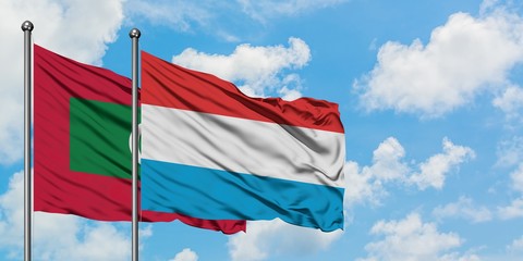 Maldives and Luxembourg flag waving in the wind against white cloudy blue sky together. Diplomacy concept, international relations.