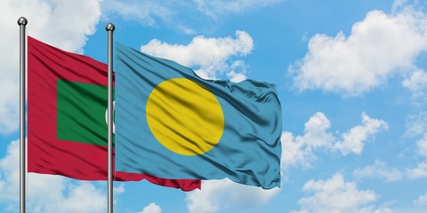 Maldives and Palau flag waving in the wind against white cloudy blue sky together. Diplomacy concept, international relations.